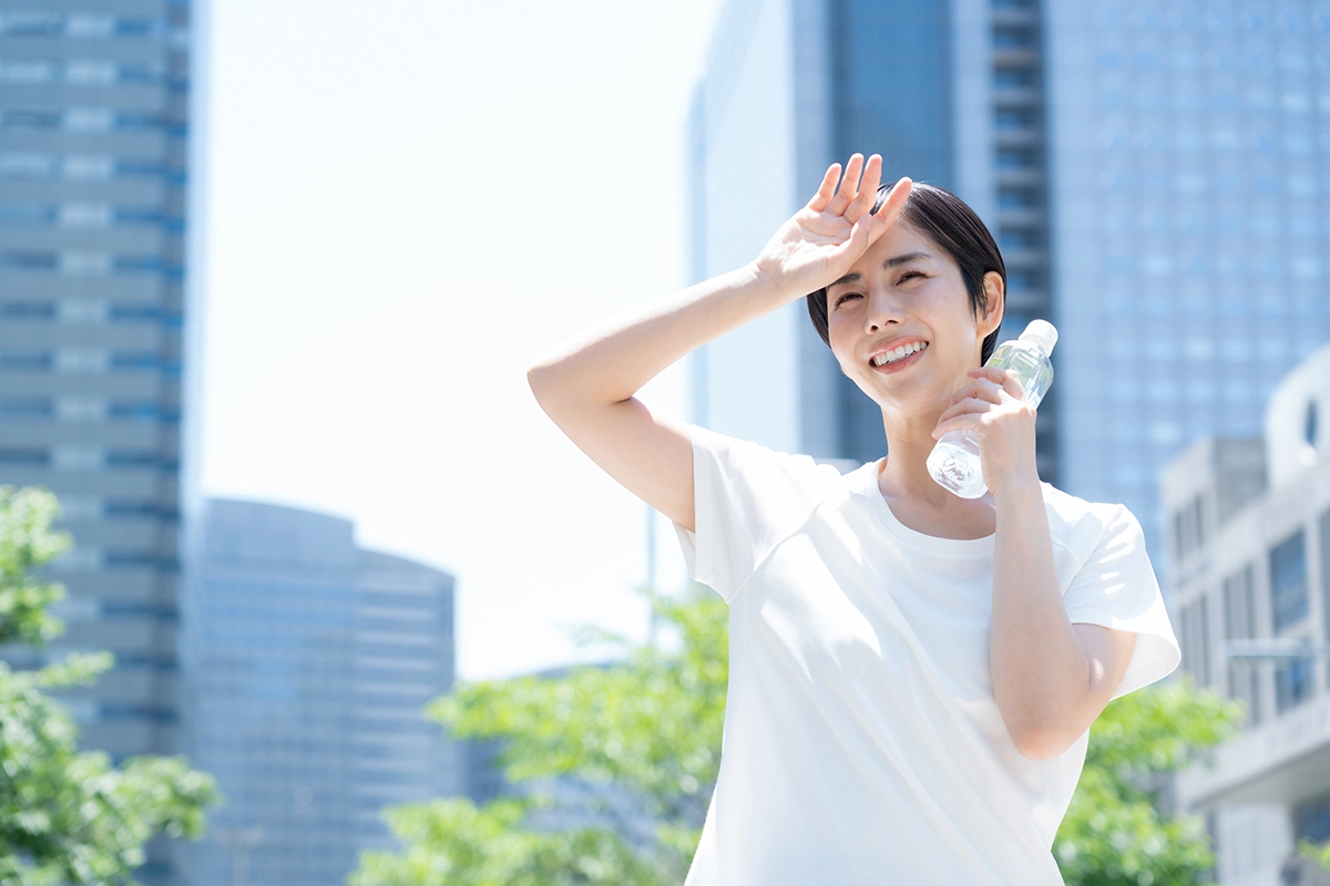 ภาพผู้หญิง ถือขวดน้ำเย็น เพื่อป้องกันอากาศร้อน ที่อาจเสี่ยงเกิดภาวะฮีทสโตรกระหว่างวัน