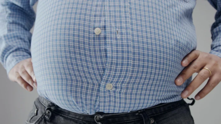 ภาพชายสูงวัยใส่เสื้อเชิ้ตที่มีภาวะอ้วนลงพุง